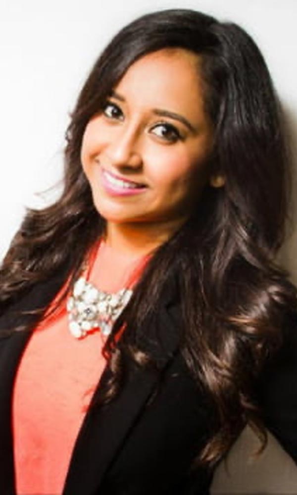 Smiling man with arms crossed, wearing a navy shirt, standing outdoors by the water.