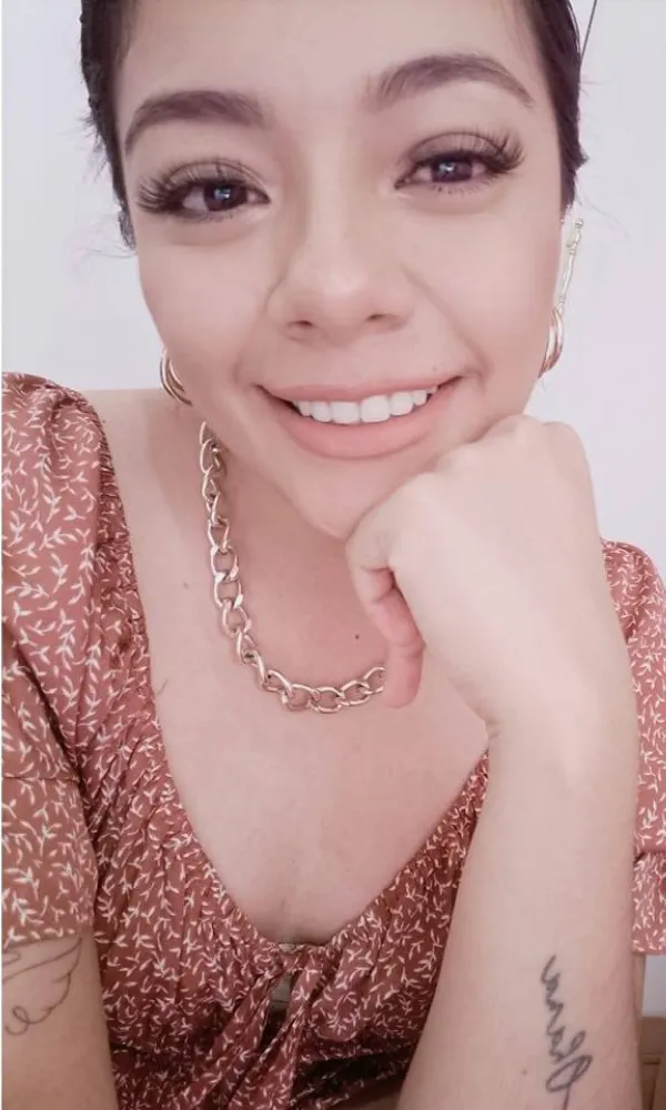 Smiling man with arms crossed, wearing a navy shirt, standing outdoors by the water.