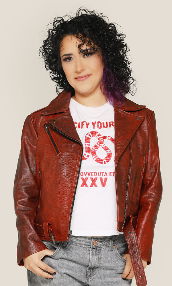 Smiling man with arms crossed, wearing a navy shirt, standing outdoors by the water.