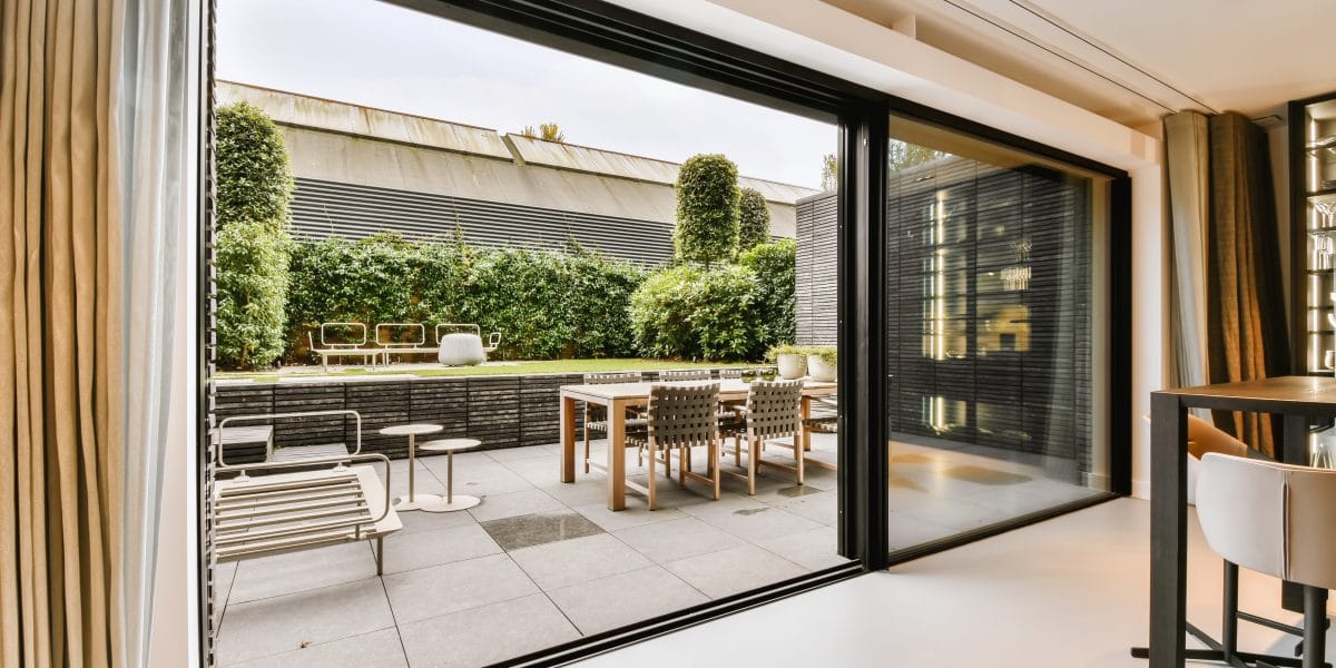 modern door installation Modern open-plan living area with glass doors leading to a stylish patio with dining table, chairs, and greenery. modern door installation Modern open-plan living area with glass doors leading to a stylish patio with dining table, chairs, and greenery.